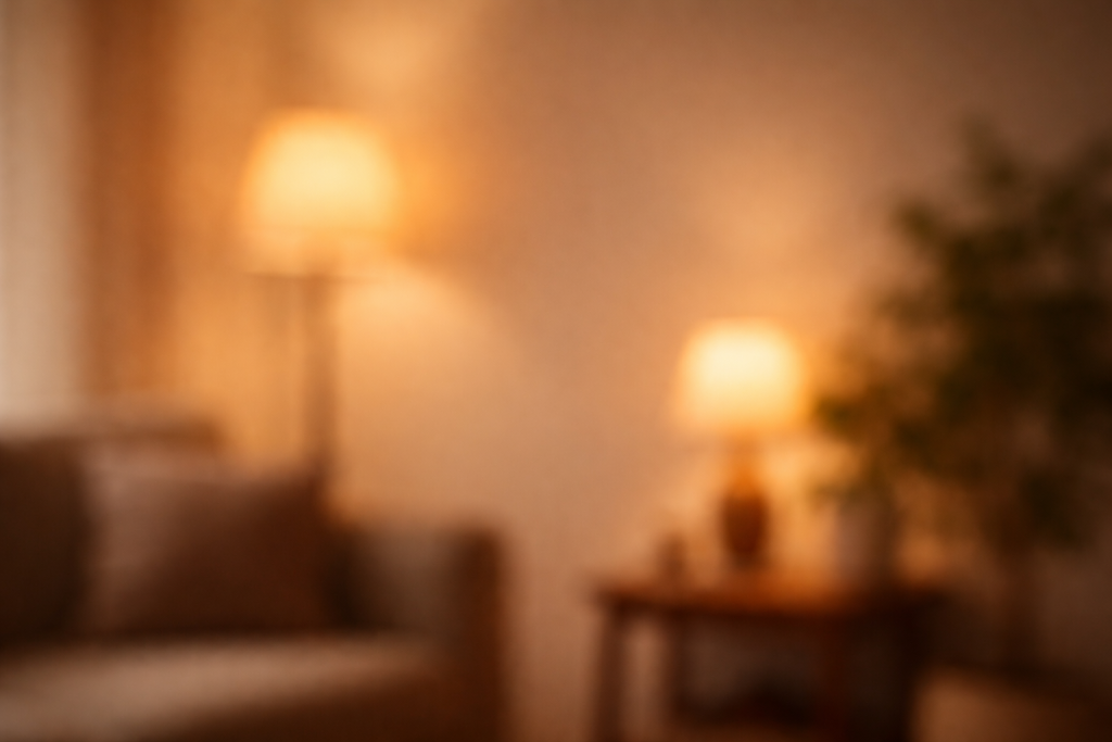 Diskret baggrund til testimonials: sløret, stemningsfuldt interiør med fokus på varm belysning i baggrunden og rolig, ensartet tone, så tekst kan ligge ovenpå uden forstyrrelser.